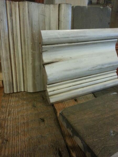 Stacks of white decorative molding leaning against a wall in a workshop or warehouse.