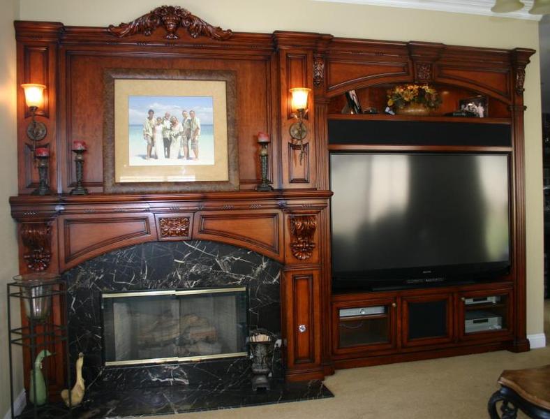 Ornate carved wood fireplace with TV built into matching entertainment center in a living room