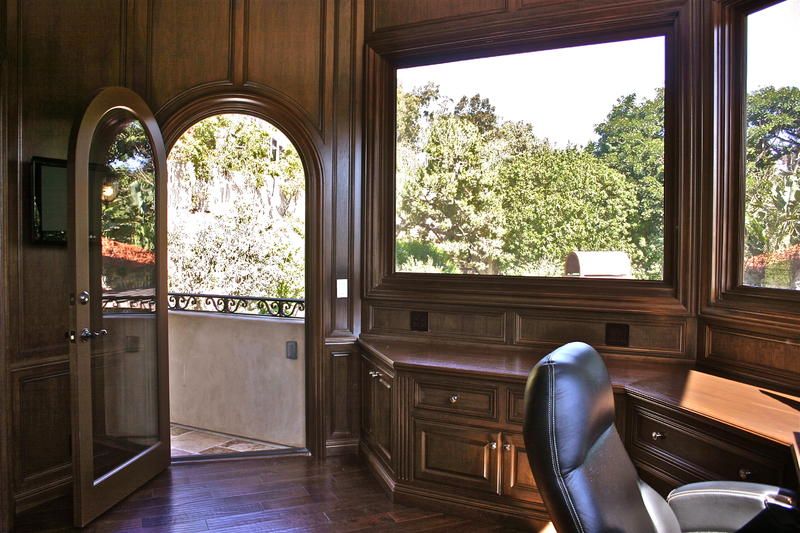 Elegant room with arched windows, open balcony door, and wooded view beyond.