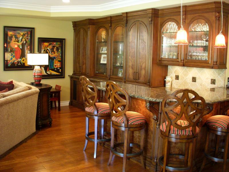 Warm kitchen with wood cabinets, granite island, barstools, and polished hardwood floors.