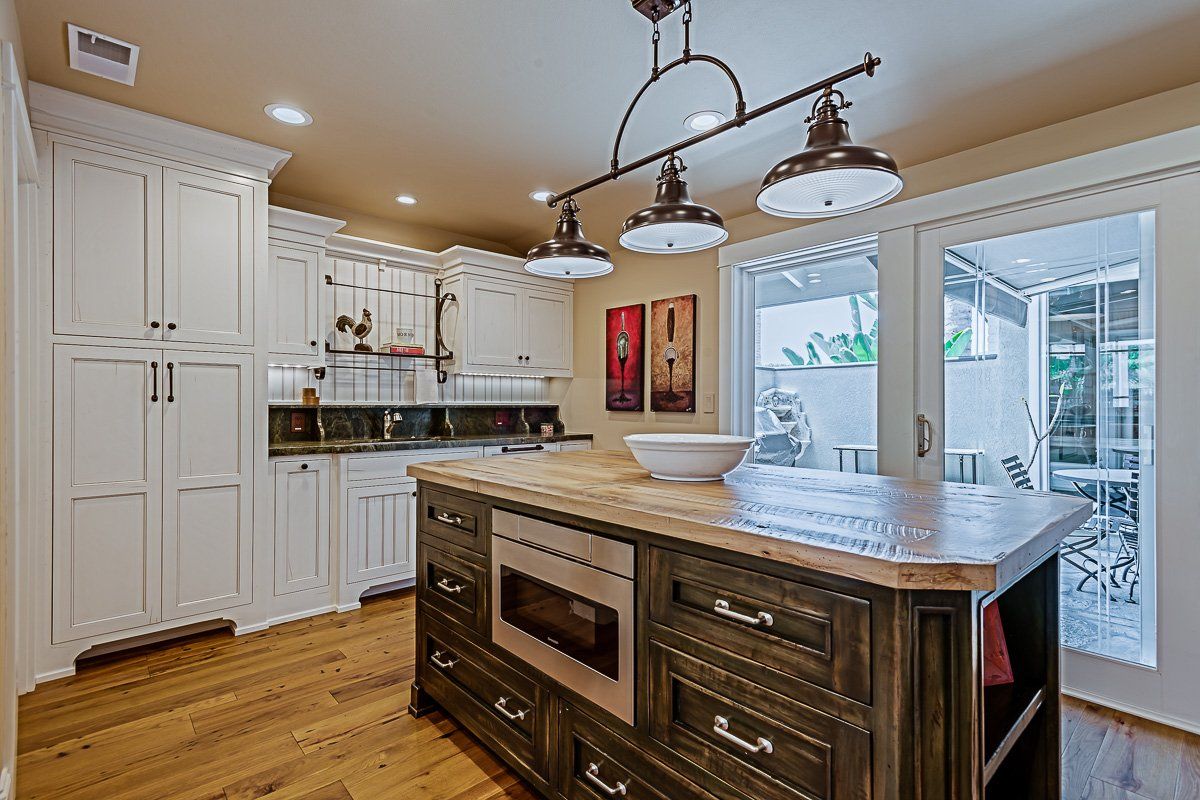 Bright white kitchen with island, hanging lights, and glass doors to a patio.