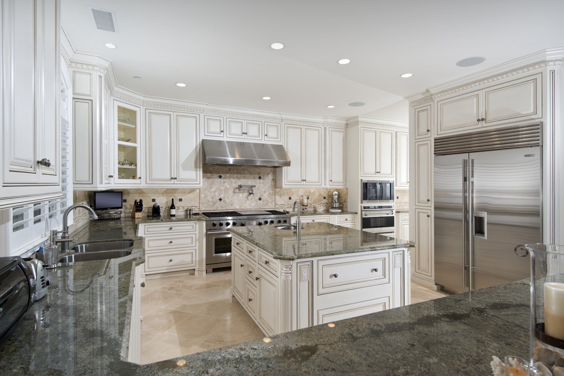 Bright white luxury kitchen with granite counters, stainless appliances, and central island