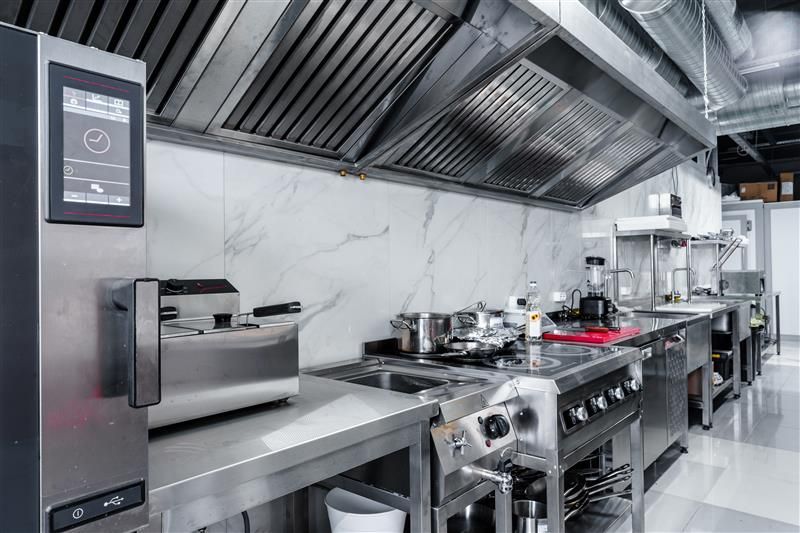 Commercial kitchen with stainless steel appliances, vent hood, and a digital control panel.
