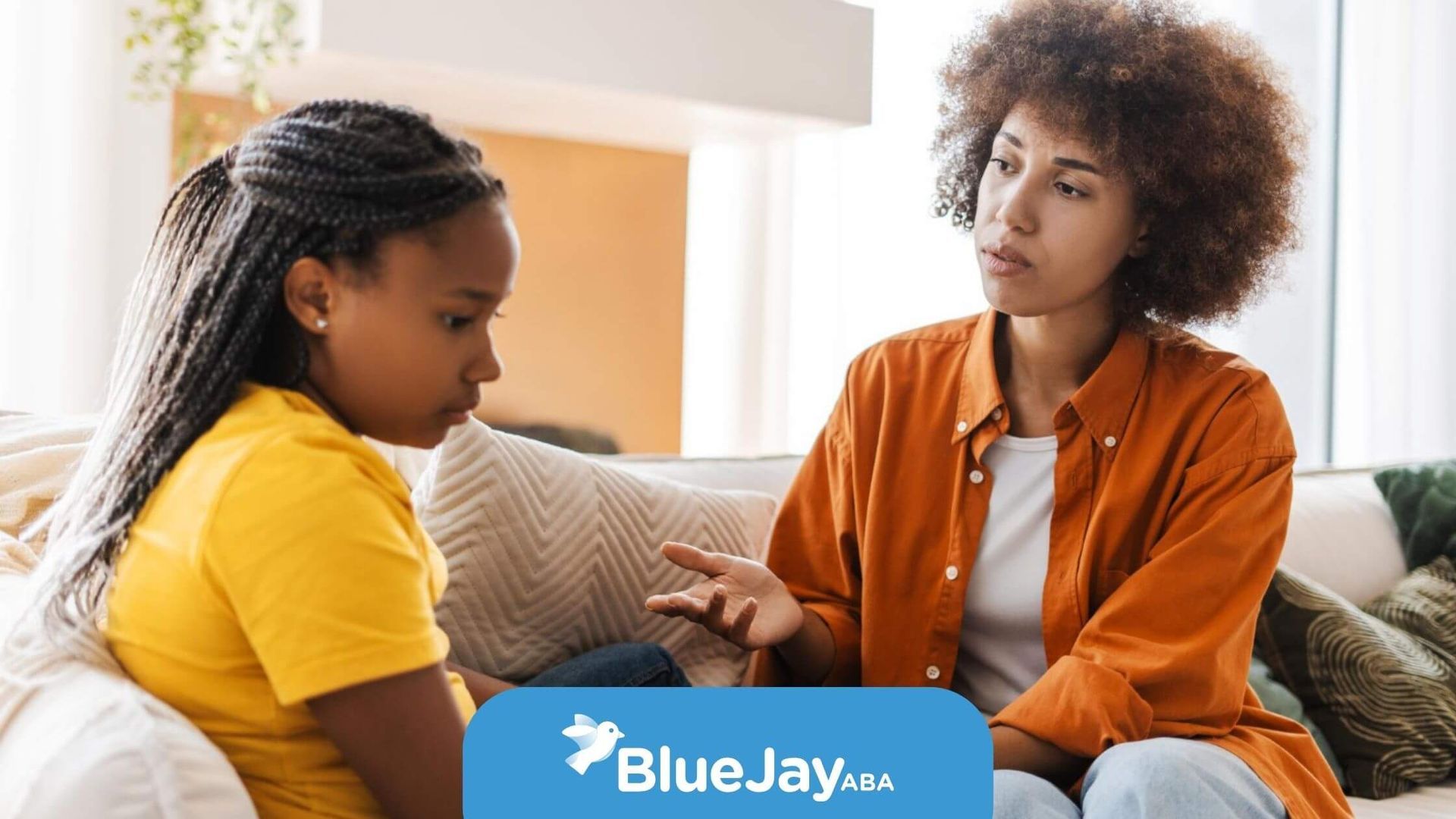 BCBA comforting a child during a conversation on a sofa.