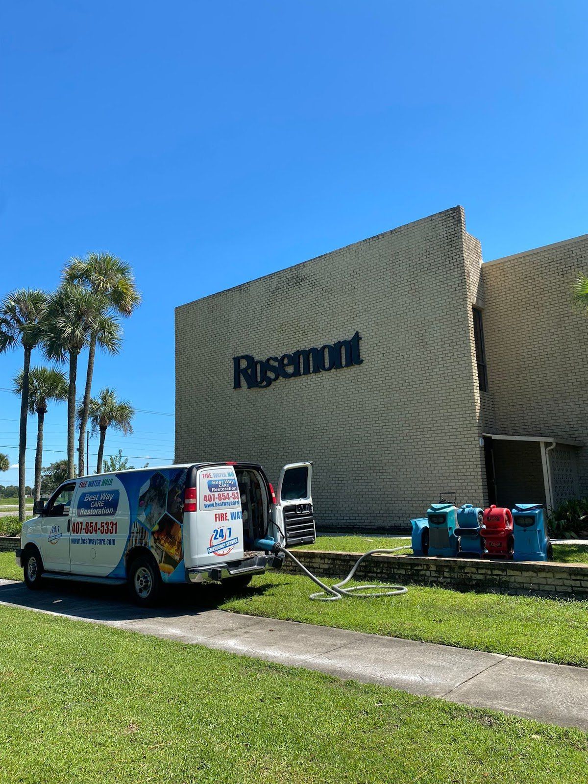 A van with company logos is parked in front of the Rosemont building with cleaning supplies.