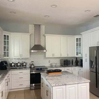 White kitchen with granite countertops, stainless steel appliances, and island.