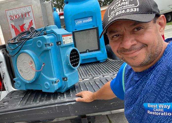 Man smiling in a truck bed with two blue dehumidifiers.