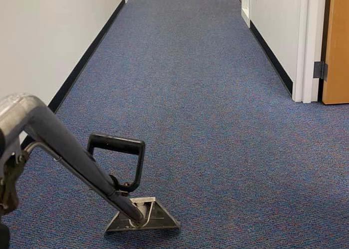 Carpet cleaning in a hallway, dark blue carpet, silver cleaning tool visible.