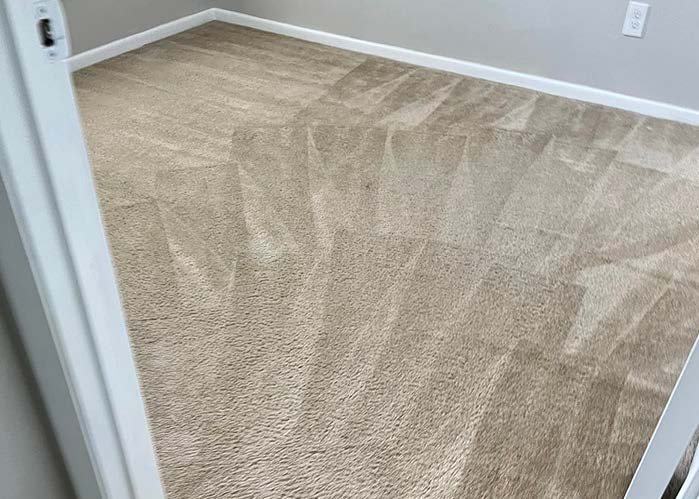 Tan carpeted room viewed from a doorway, with light-colored walls and baseboards.