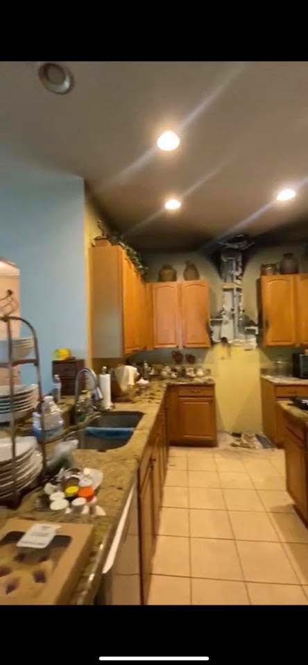 A kitchen interior with dark burn damage on the ceiling, cabinets, and appliances.