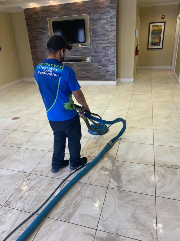 Person cleaning tile floor with a machine in a hallway.