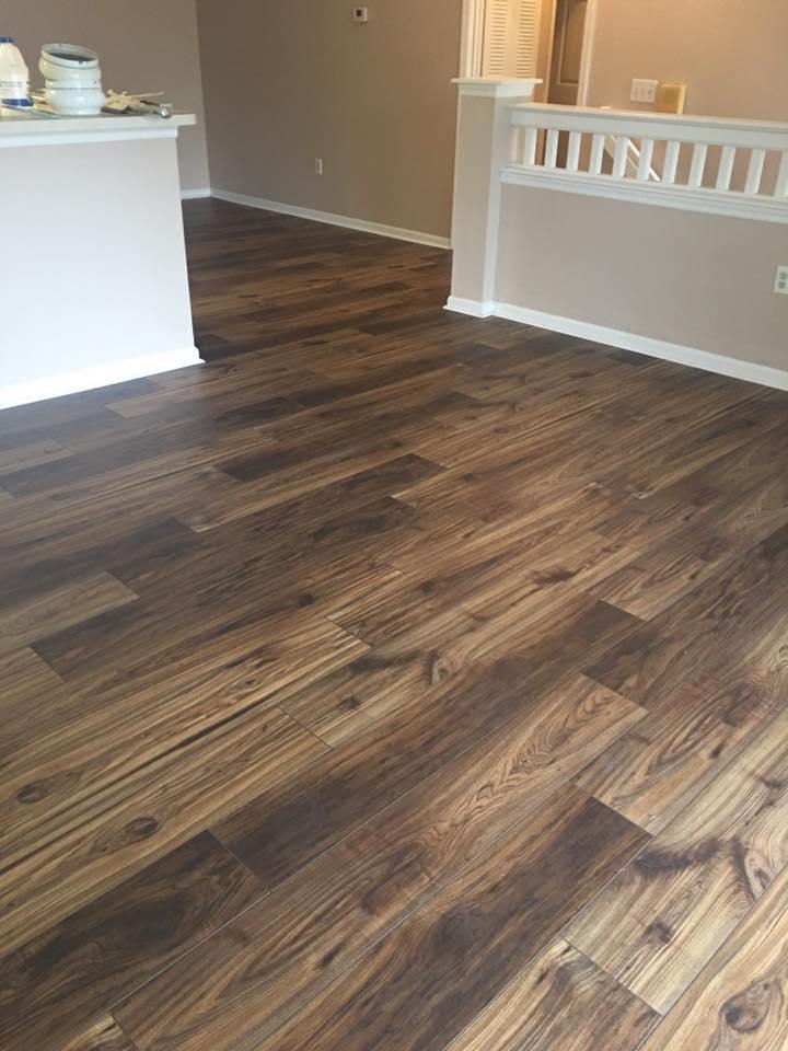 Dark brown wood-look flooring installed in a room with tan walls and white trim.