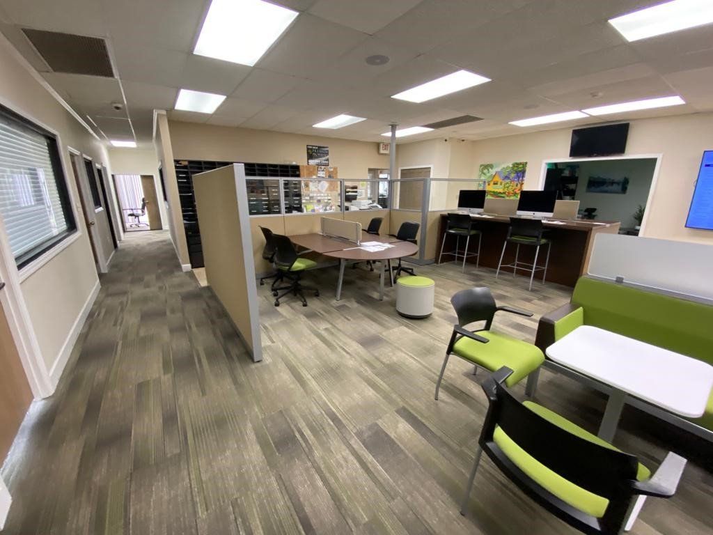 Office interior with desks, chairs, and dividers; various work stations, neutral color scheme.