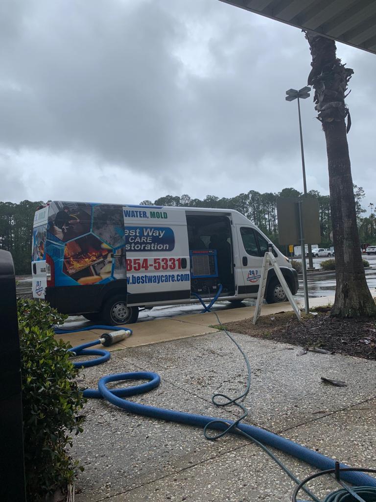 Service van cleaning outdoors with blue hoses, under a cloudy sky.