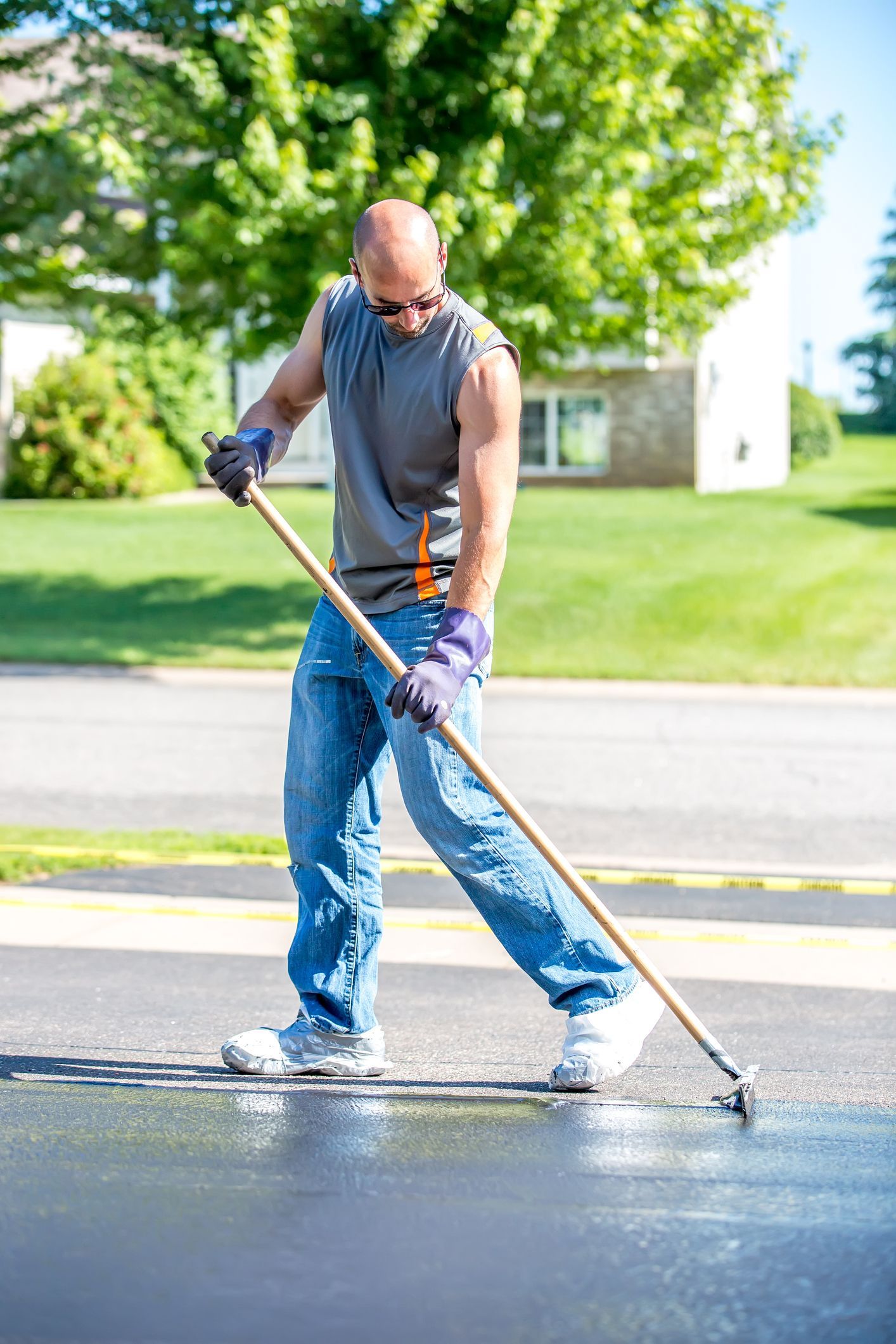 A Man Is Doing Cement Work in a Driveway — Paving Contractors In Butler, PA A Man Is Doing Cement Work in a Driveway — Paving Contractors In Butler, PA