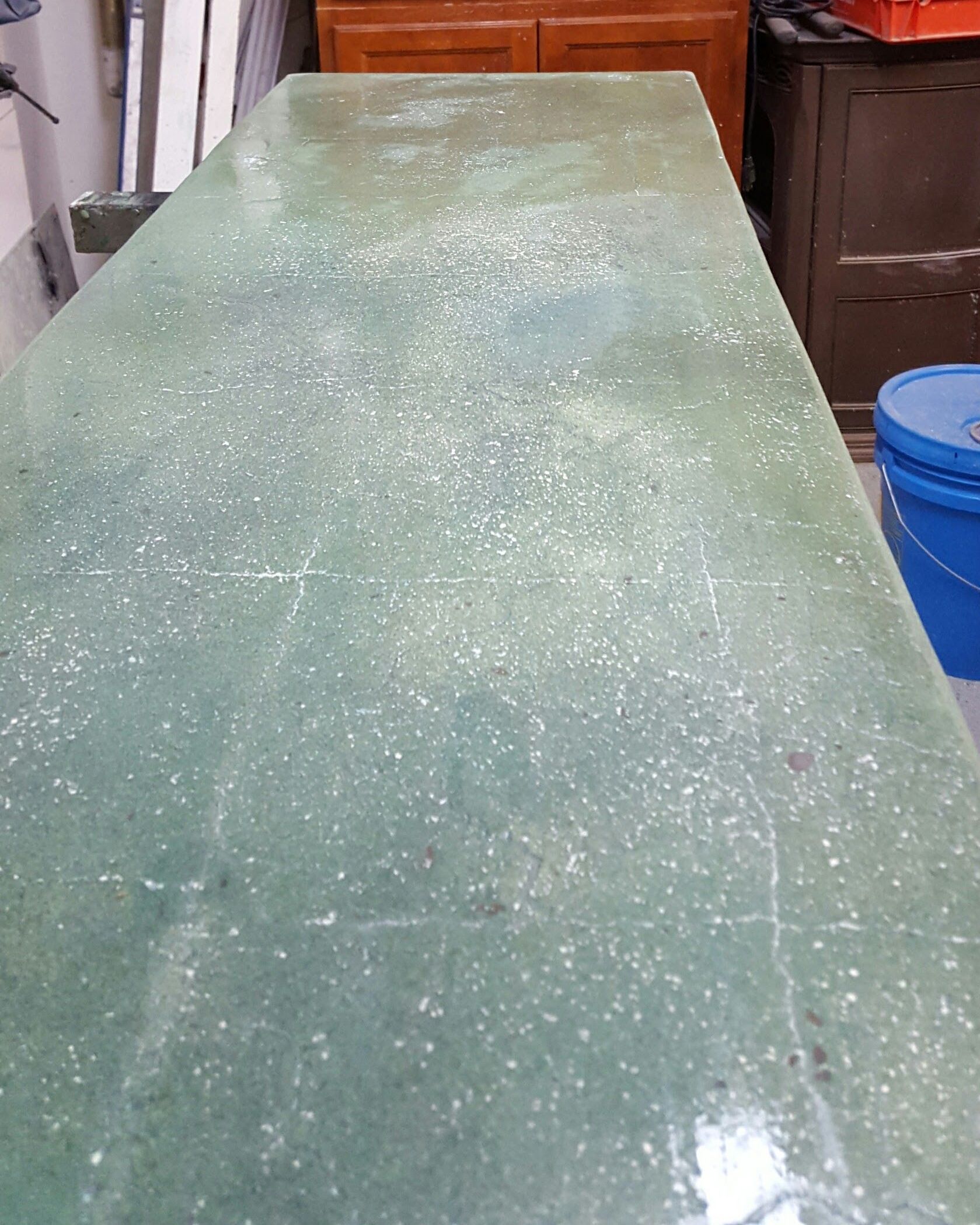 A green table with a blue bucket in the background.