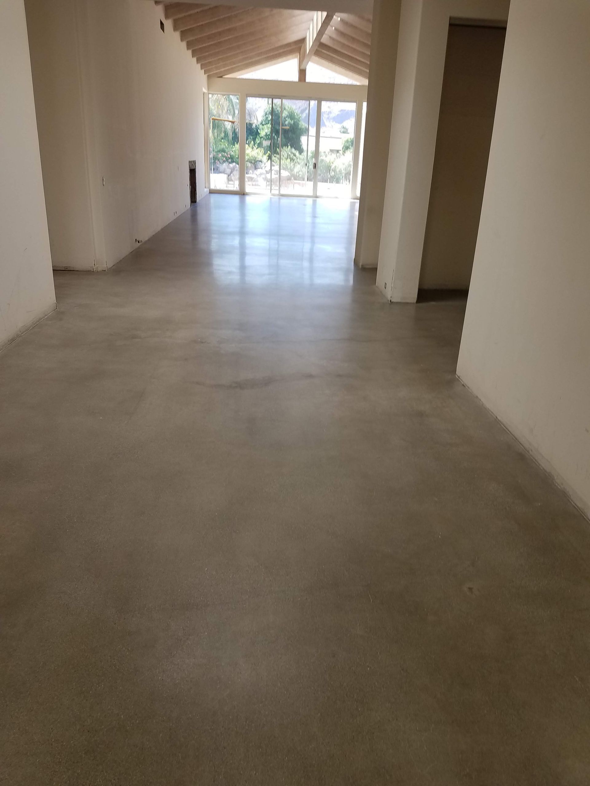 A large empty room with a concrete floor and a lot of windows.