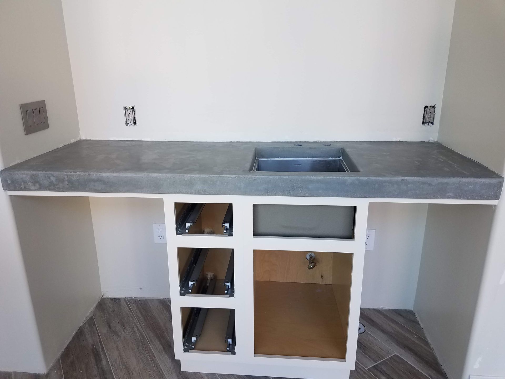A kitchen with a concrete counter top and a sink