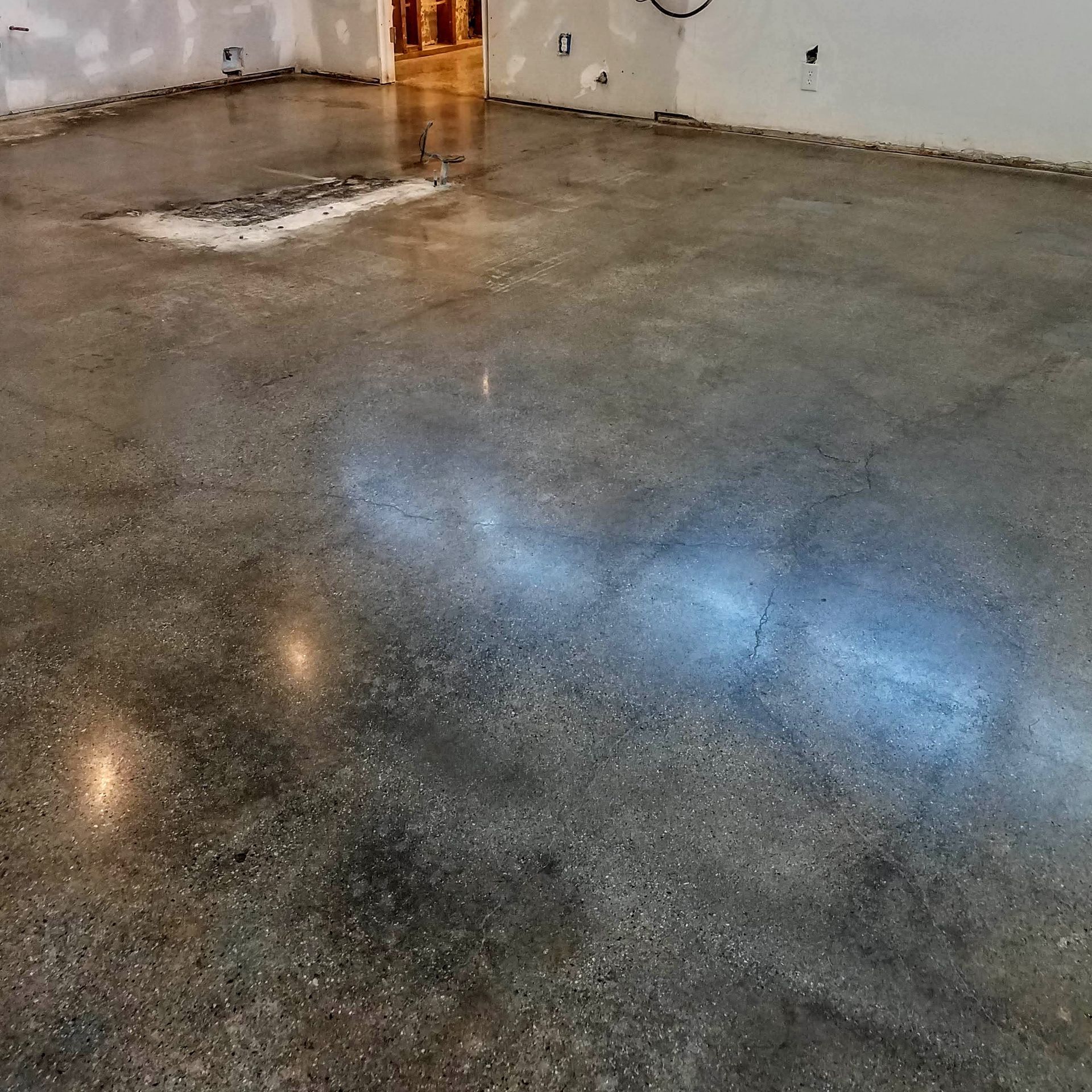 A large room with a shiny concrete floor and white walls.