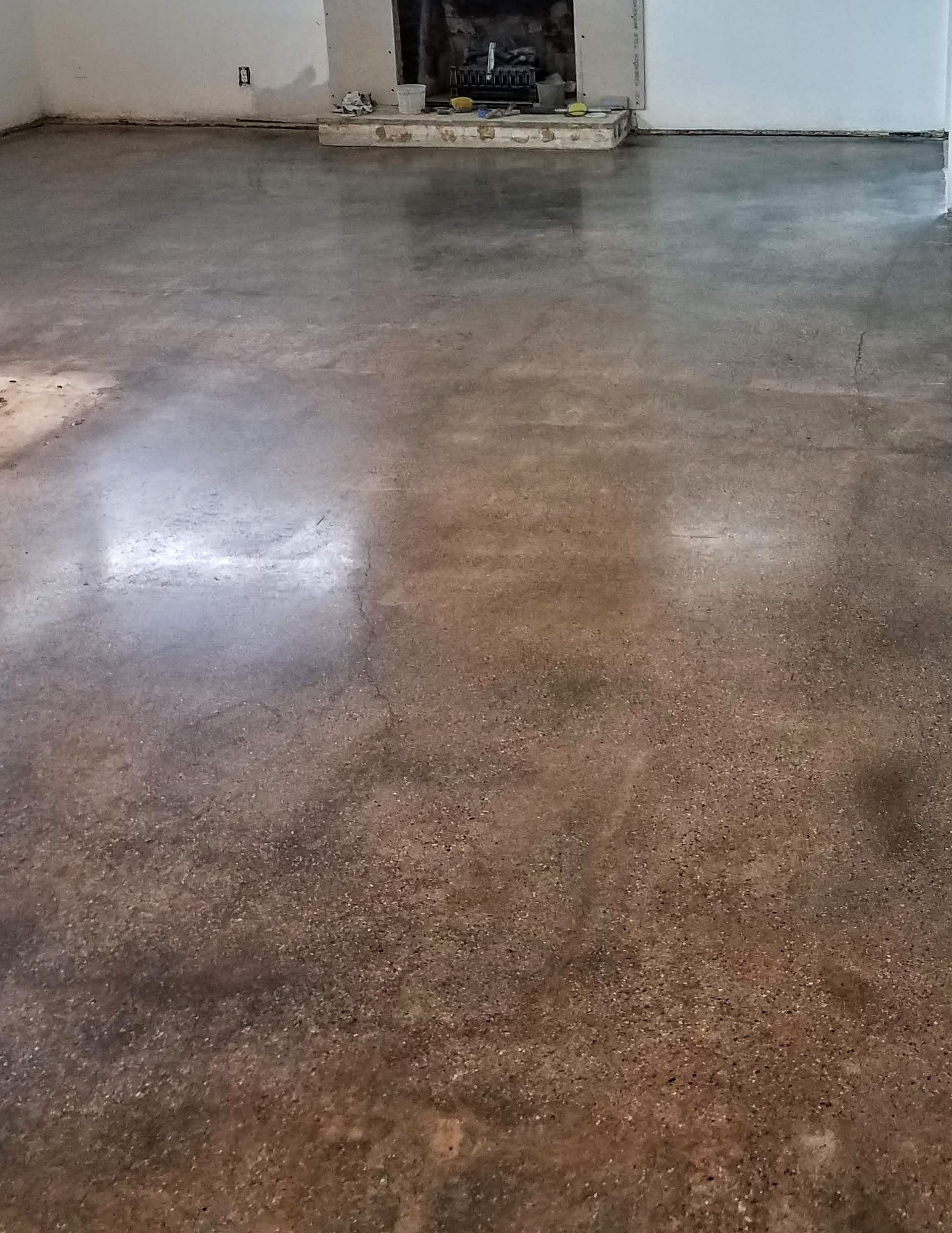 A living room with a concrete floor and a fireplace.