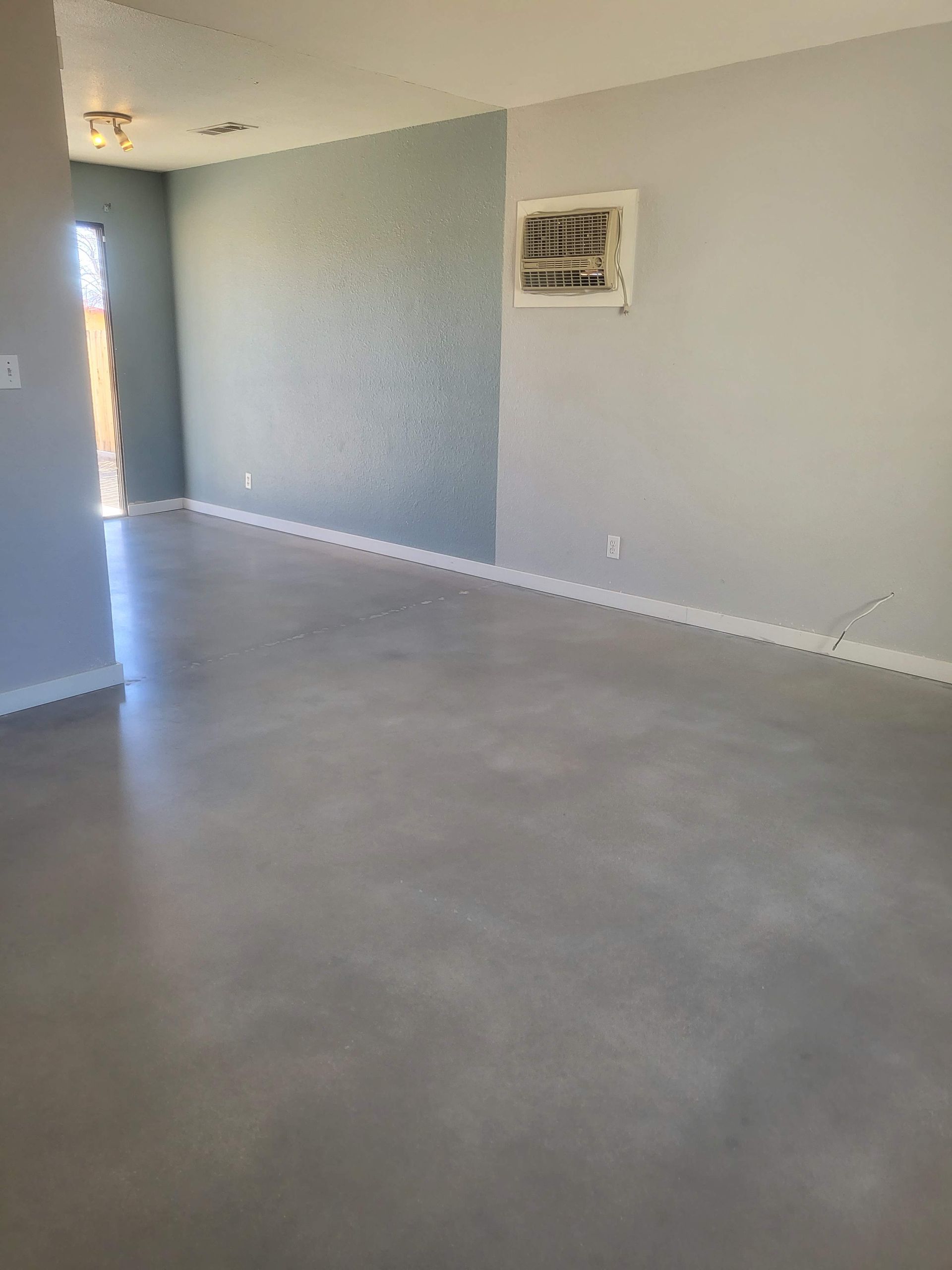 An empty living room with a picture on the wall.