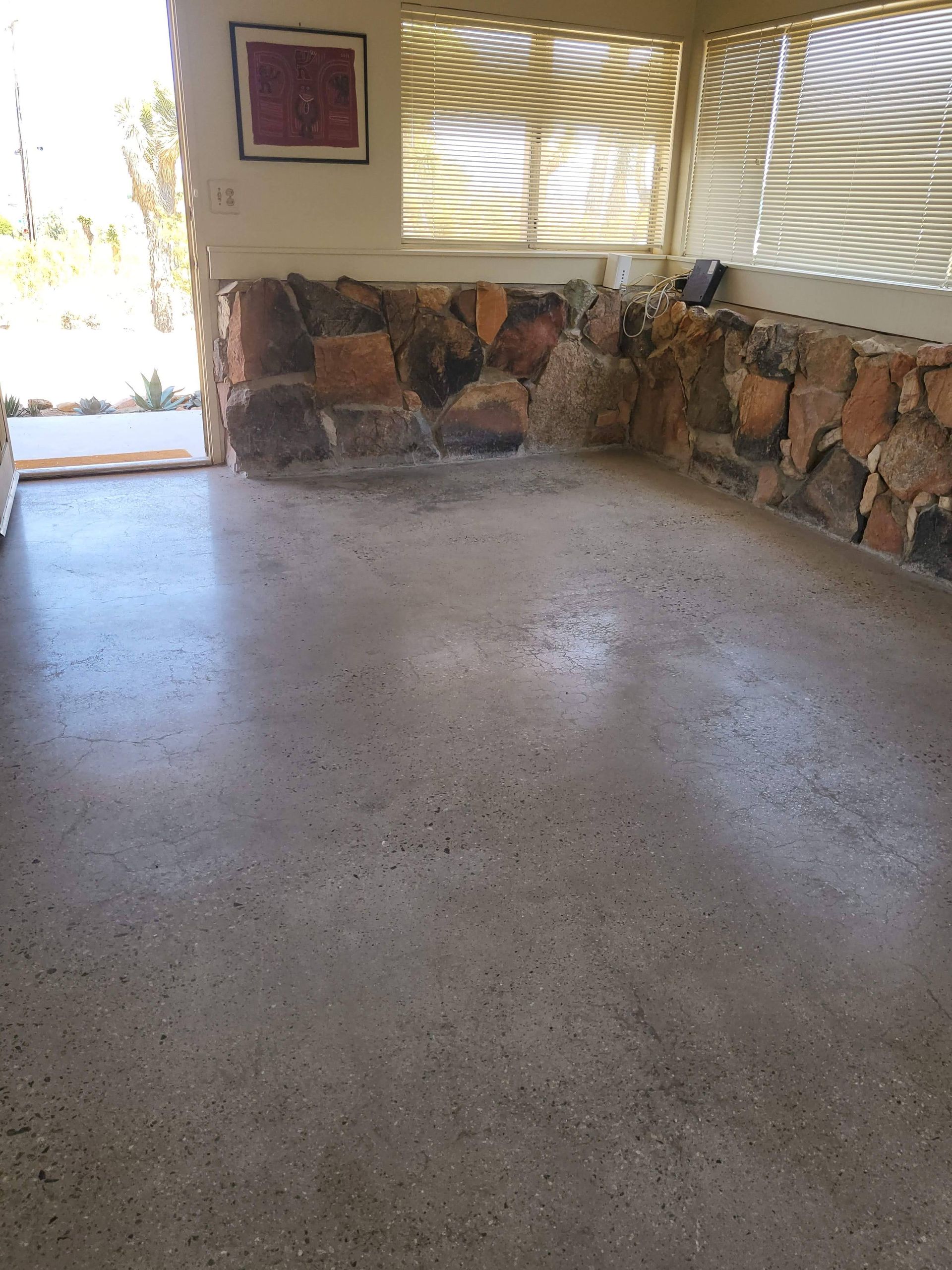 A living room with a stone wall and a concrete floor.