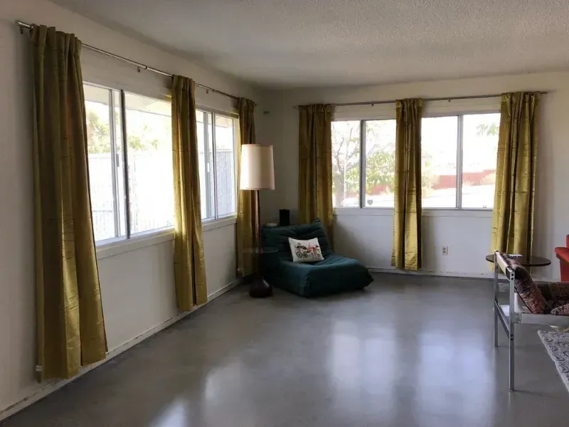 A living room with a chair , lamp , and curtains.
