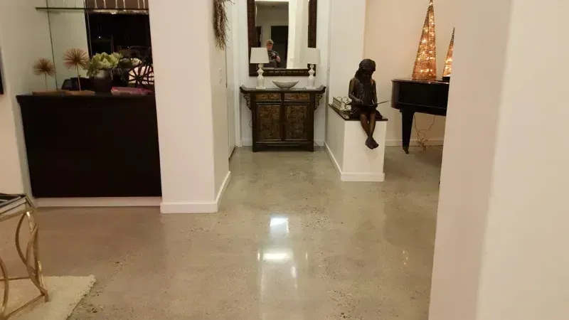 a living room with a piano and a statue on the polished concrete floor in La Quinta CA.