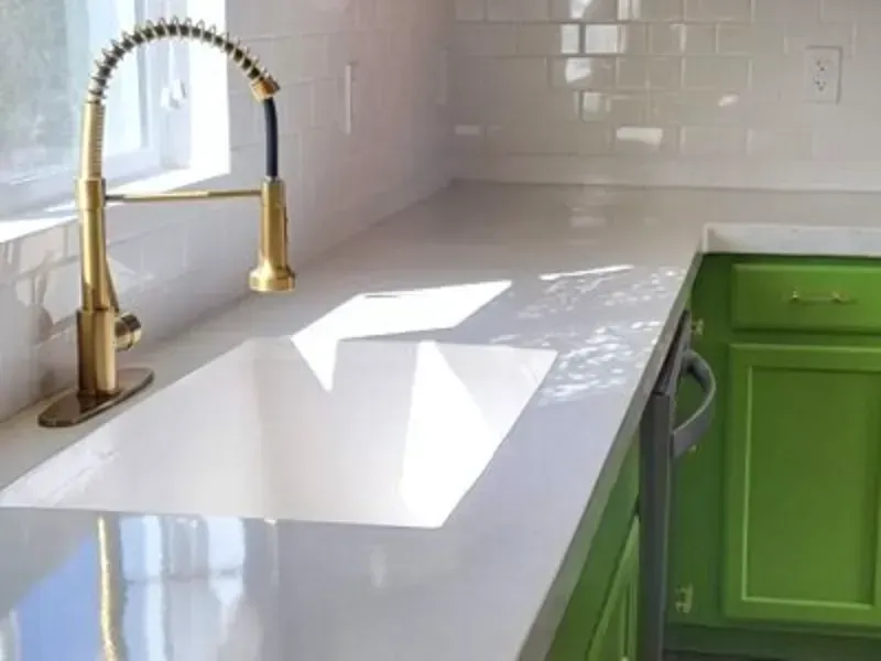 White cabinets with a gray concrete countertop against a gray wall.