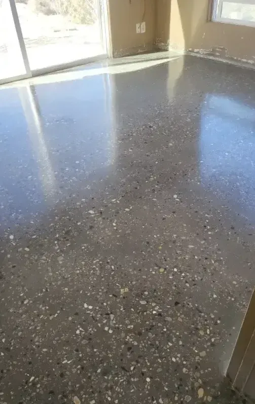 A highly polished concrete floor with visible aggregate, reflecting light in a bright, modern room.