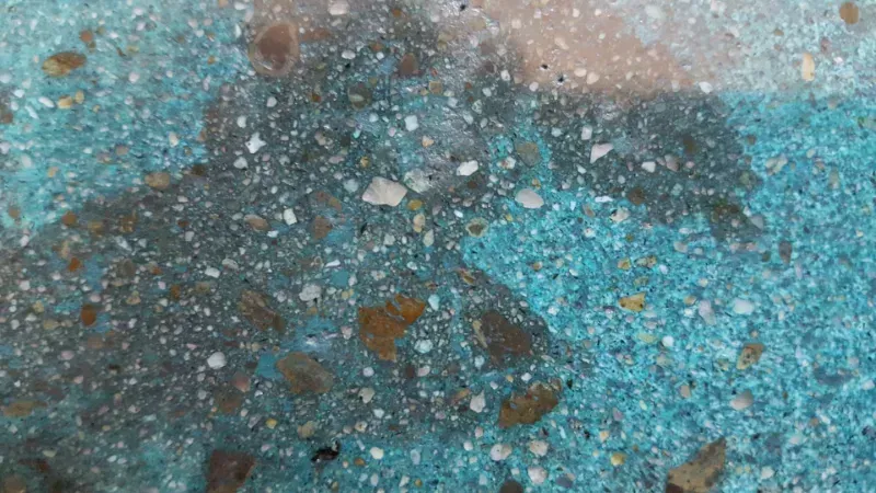 A close up of a concrete stain surface with a lot of small stones on it.