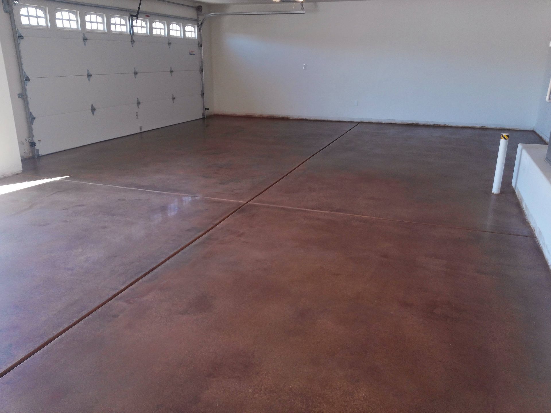 A large empty garage with a concrete floor and a garage door.