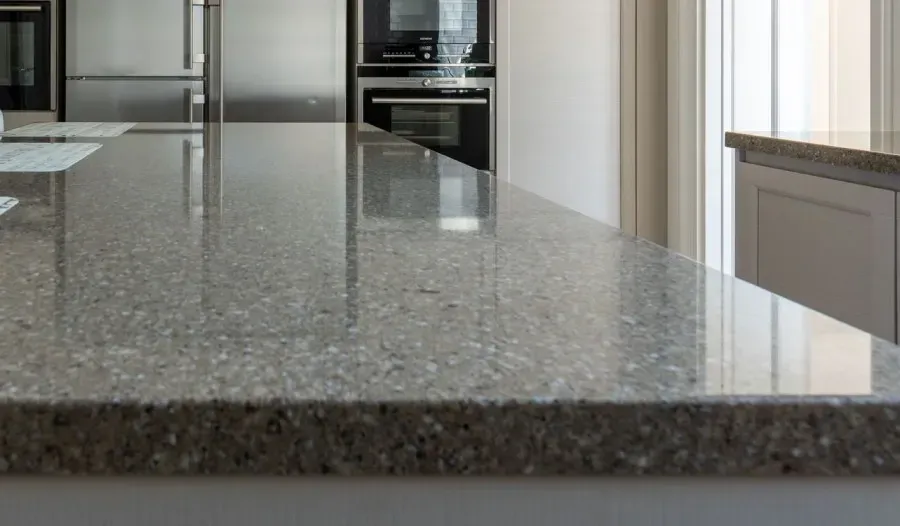 Modern kitchen with a glossy gray granite countertop and built-in stainless steel appliances.