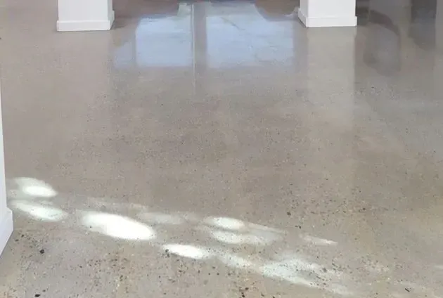 Bright empty room with polished speckled floor and sunlight reflections