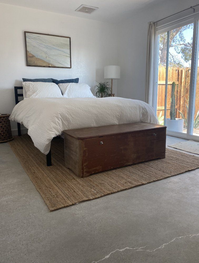 A bedroom with a polished concrete floor.