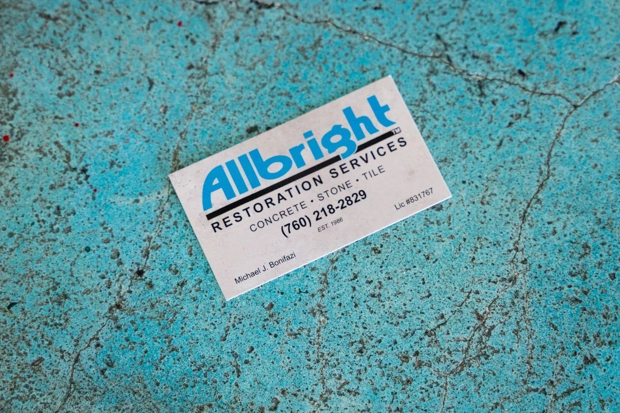 A business card for allbright restoration services is on a blue surface.
