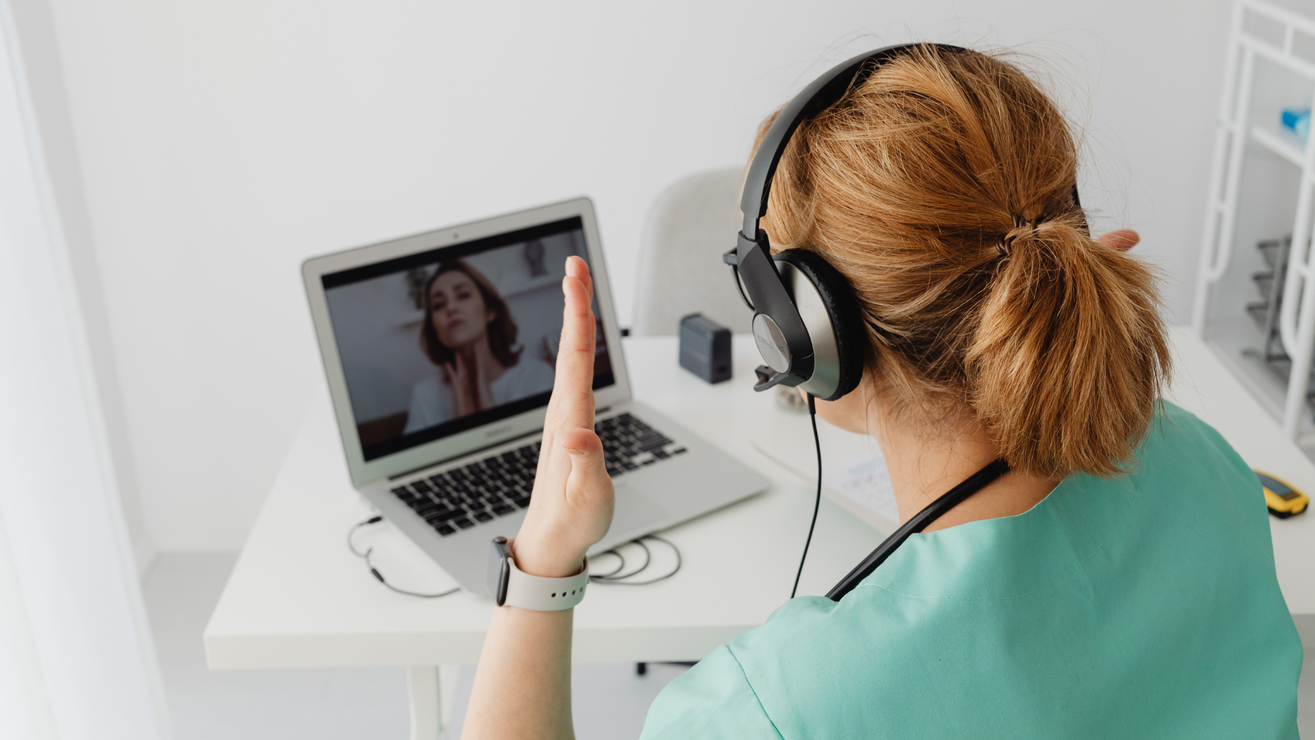 A nurse wearing headphones is having a video call on her laptop.