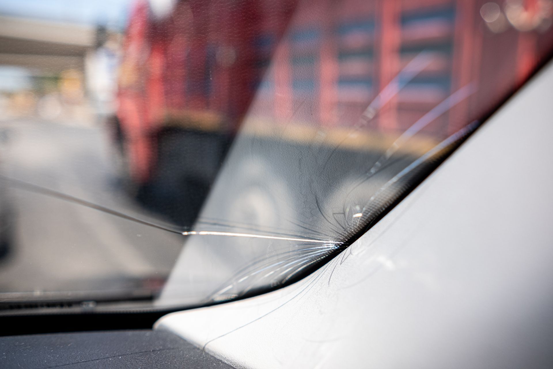 Black-gloved hand using a polishing tool on a car's headlight, detail shot, setting is inside.