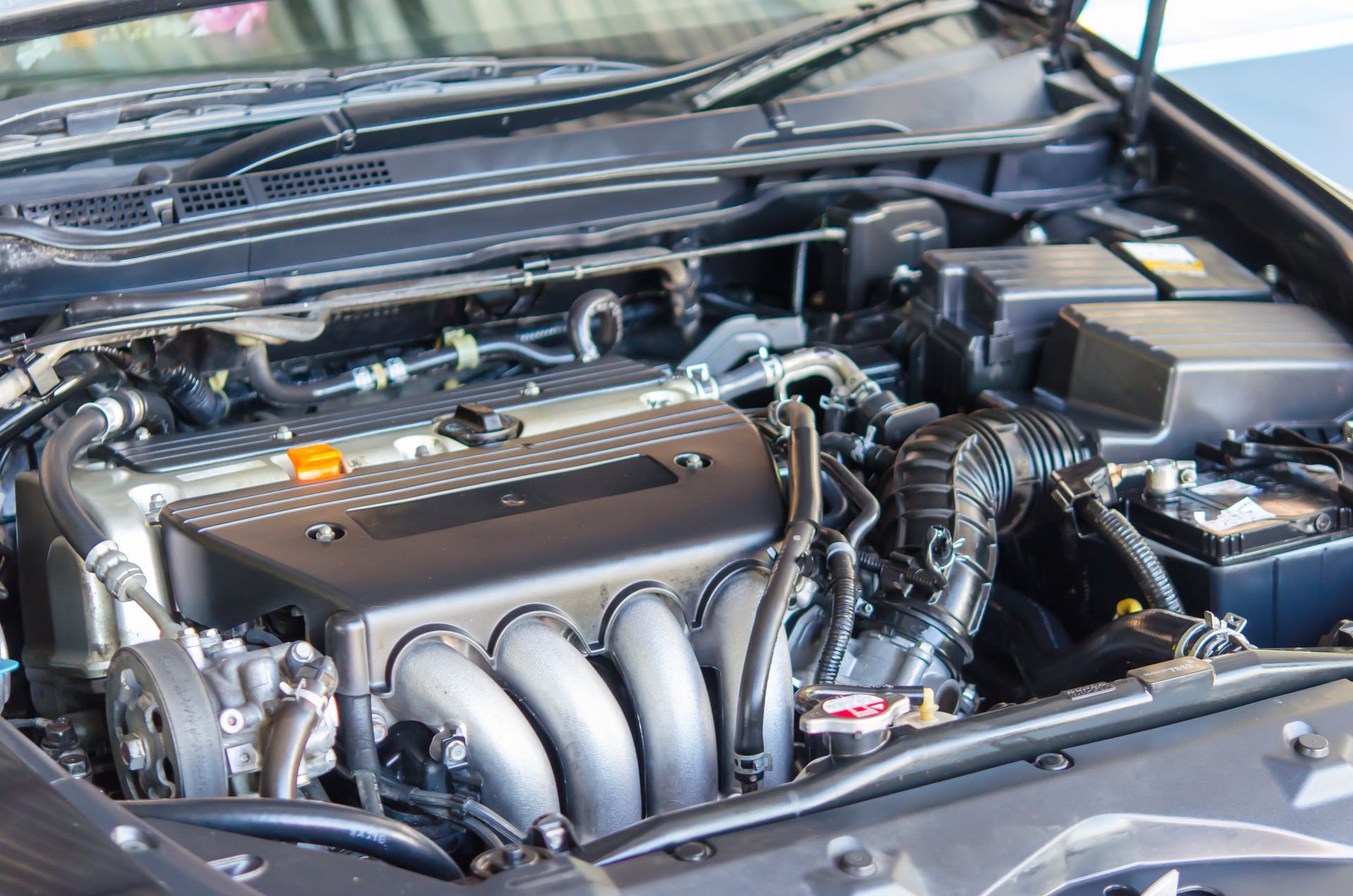 Car engine, black and silver, showing components including intake manifold and air filter.
