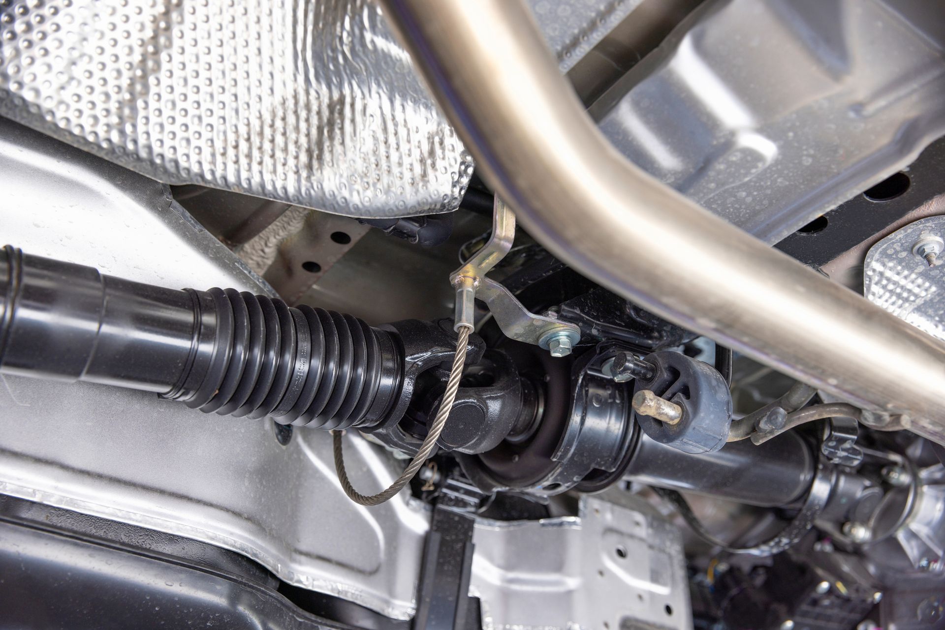 Close-up of a car's front suspension, highlighting components like driveshafts and assembly details.