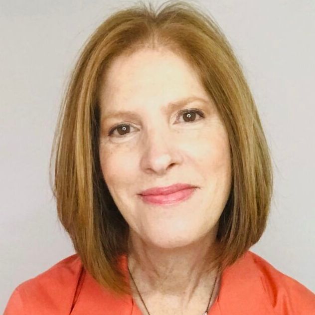 A woman wearing a red shirt and a necklace smiles for the camera.