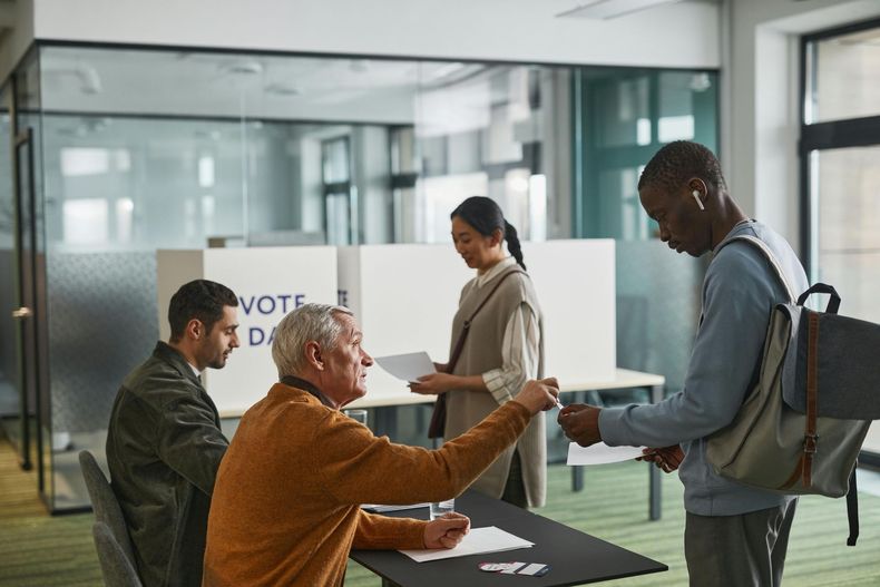 A group of people are standing around a table at a voting booth.