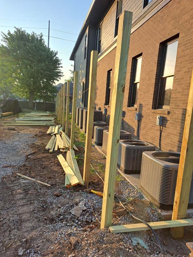 A wooden fence is being built in front of a brick building.
