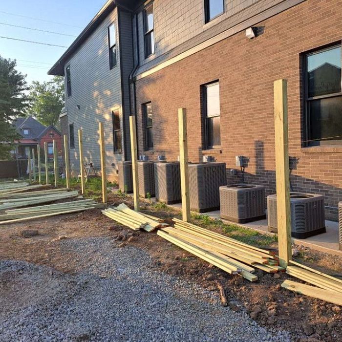 A wooden fence is being built in front of a brick building