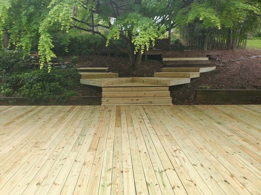 A wooden deck with stairs and trees in the background
