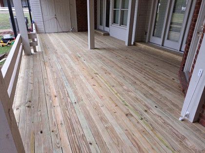 A large wooden deck with a railing and sliding glass doors.