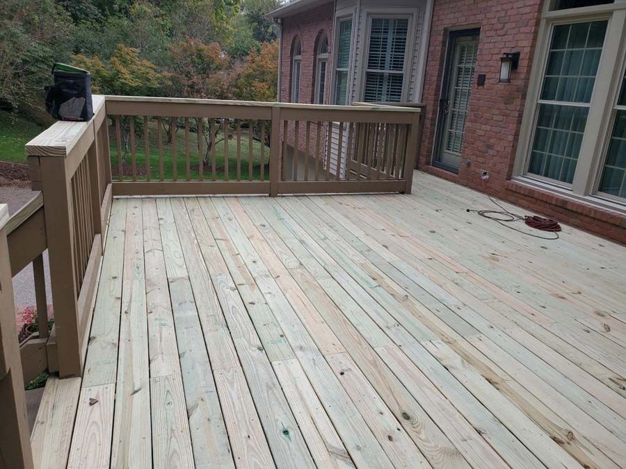 A large wooden deck is sitting in front of a brick house.