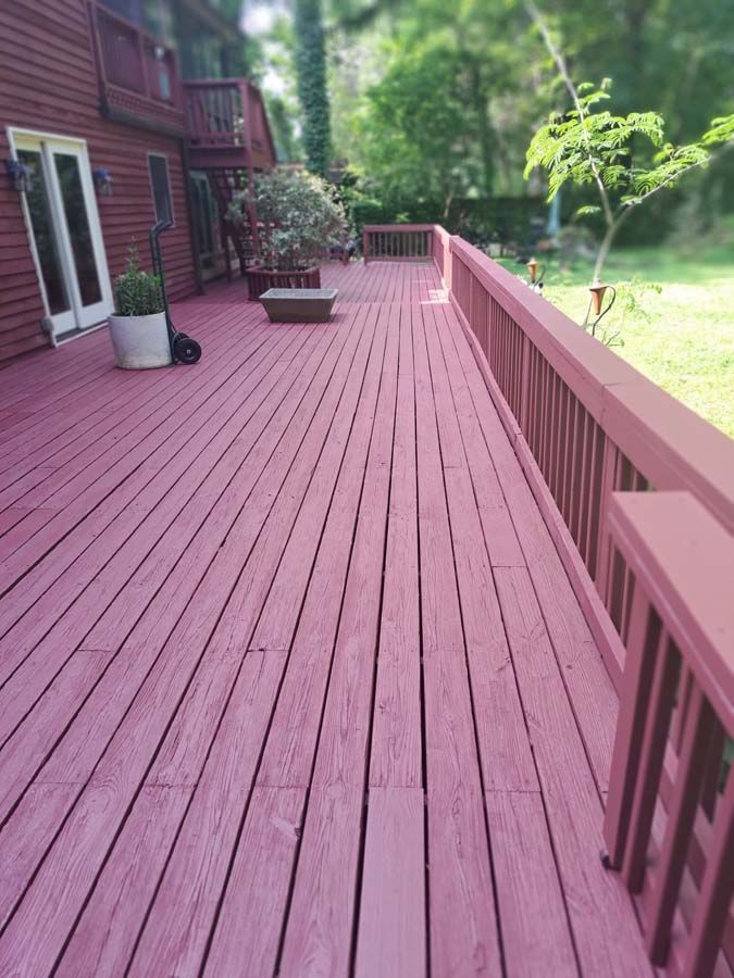 A large red deck with a railing and a house in the background
