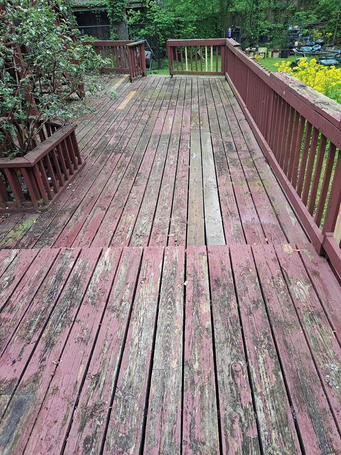 A red wooden deck with a railing and a bench.