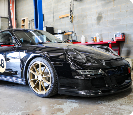 Black sports car with gold rims parked in a garage workshop | Trask Automotive